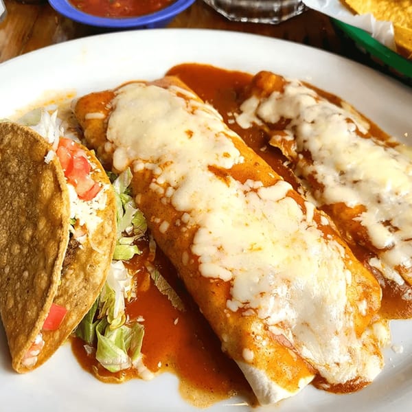 A La Calera Mexican Bar & Grill plate with two cheesy burritos and a taco with lettuce and tomatoes.