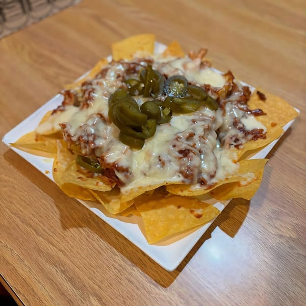 La Calera Mexican Bar & Grill's nachos with melted cheese, meat, and sliced jalapeños on a white plate.