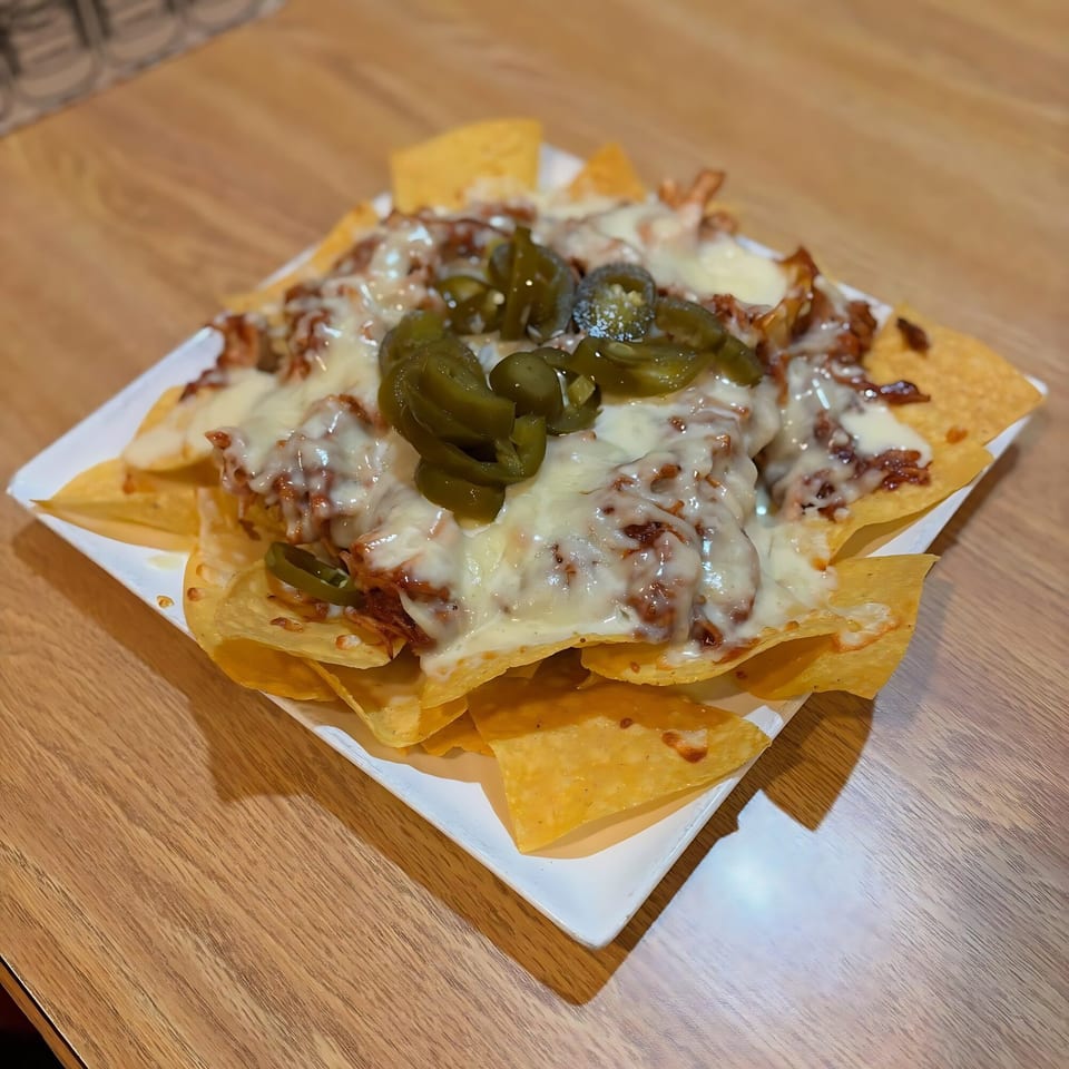 La Calera Mexican Bar & Grill's nachos with melted cheese, meat, and sliced jalapeños on a white plate.