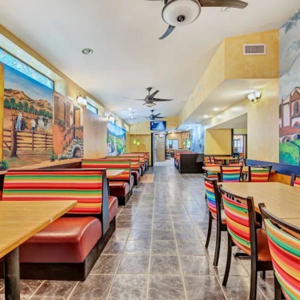 Colorful La Calera Mexican Bar & Grill dining room with murals, booths, and tables with striped chairs.