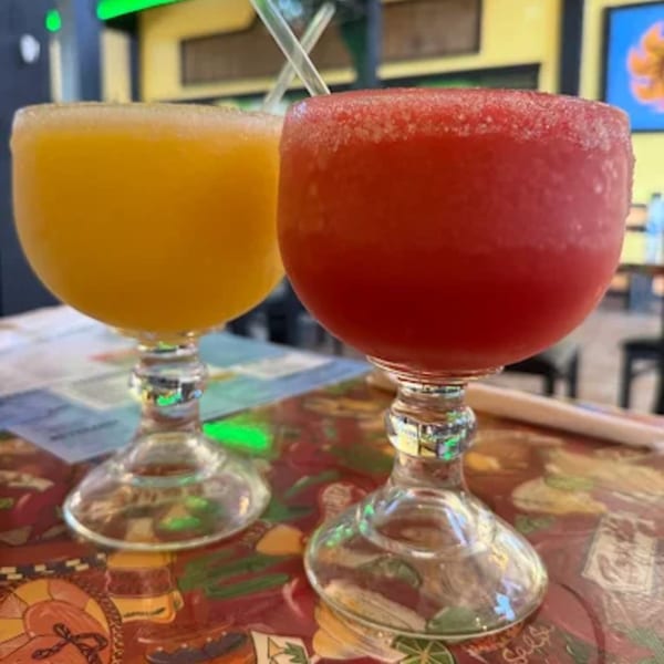 Two La Calera Mexican Bar & Grill margaritas, one yellow and one red, on a colorful table.