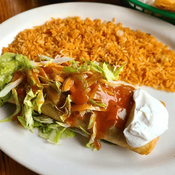 A La Calera Mexican Bar & Grill burrito topped with sauce, lettuce, and sour cream, served with rice.