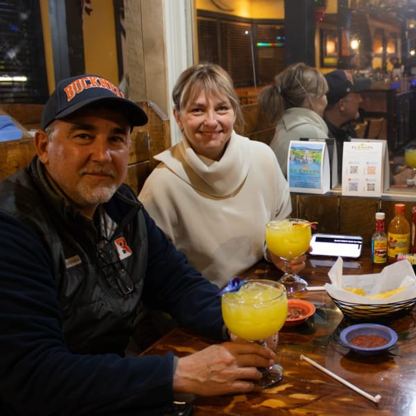 A couple smiles at the camera while enjoying drinks and chips with salsa at La Calera Mexican Bar & Grill.