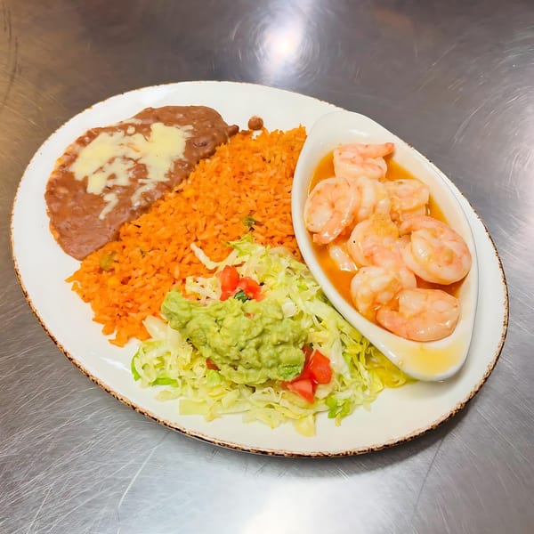 A Mexican shrimp dish with rice, refried beans, guacamole, and shredded lettuce on a white plate.
