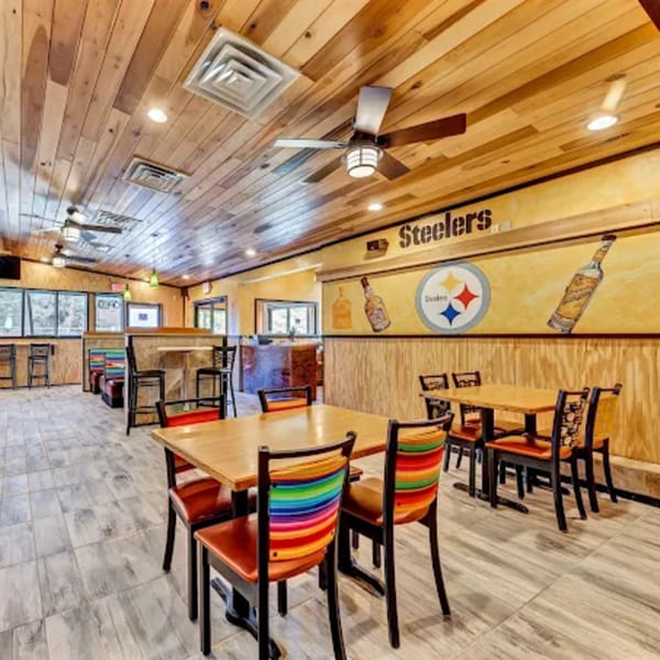 Interior of La Calera Mexican Bar & Grill with wooden tables, colorful chairs, and Steelers decor.