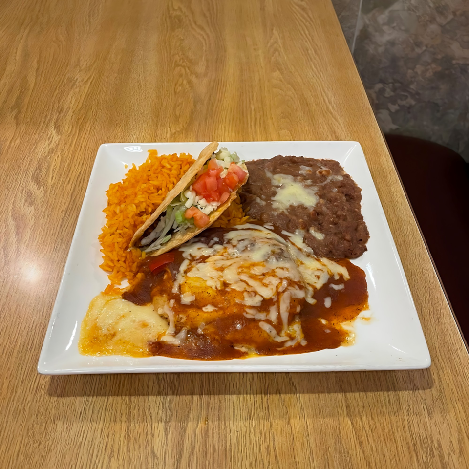 A La Calera Mexican combo plate with enchiladas, rice, refried beans, and a taco.